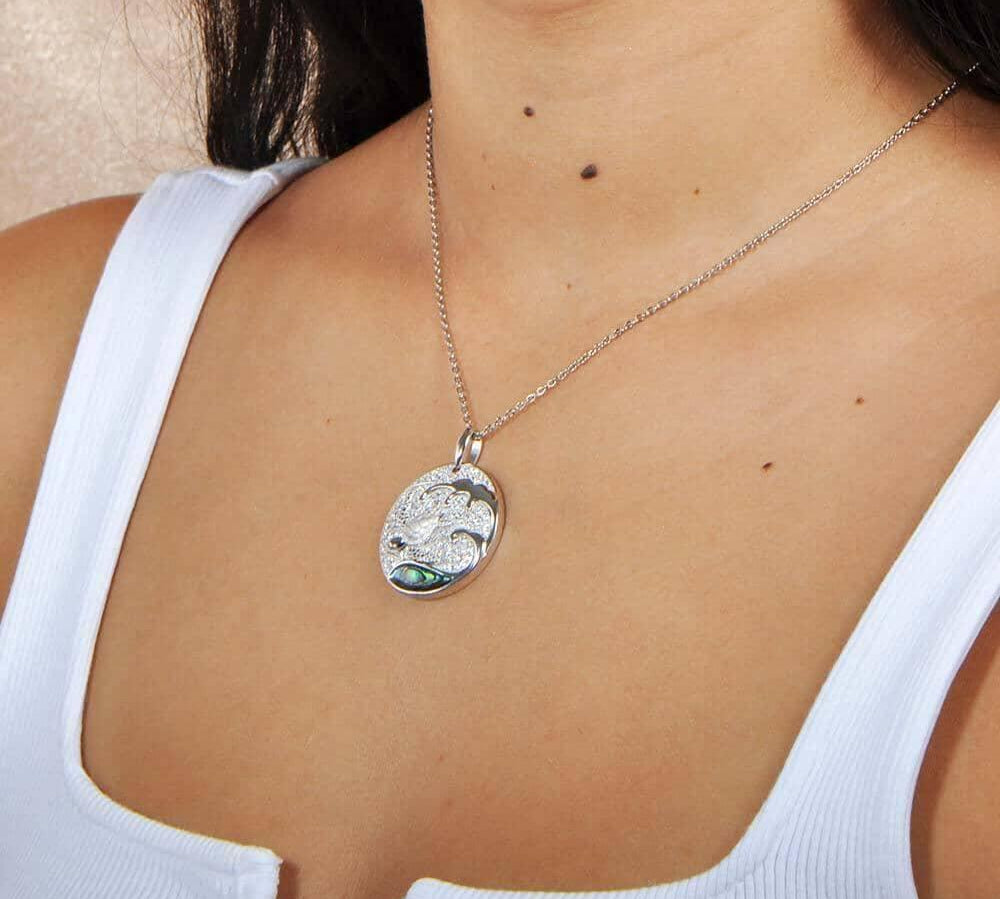 Sterling silver medallion pendant with a turtle swimming away from the abalone tides, worn by a model