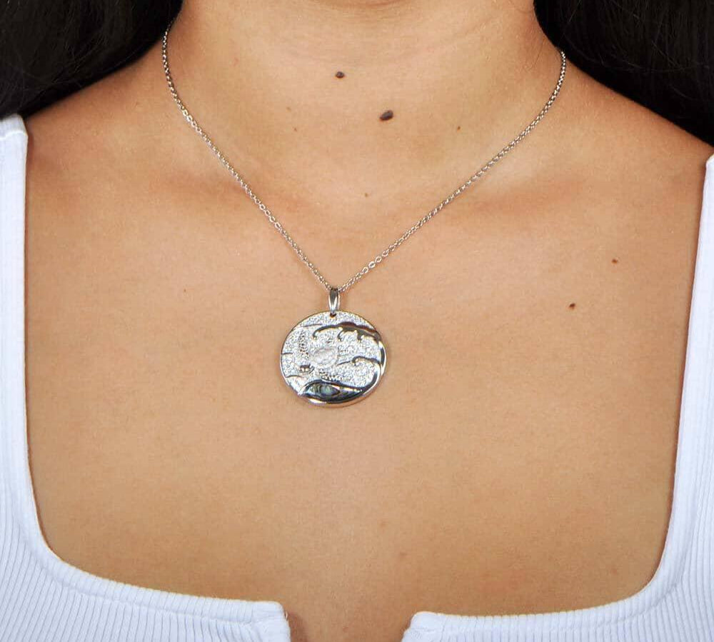 A model wearing a Sterling silver medallion pendant with a turtle swimming away from the abalone tides. 