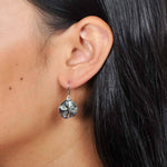 Sterling silver abalone earrings with a sand dollar design worn by a model. 