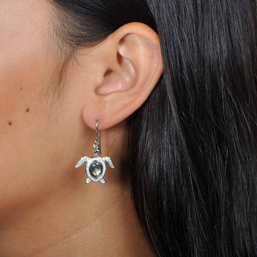 Sterling silver, abalone, and pave sea turtle hook earring worn by a model.