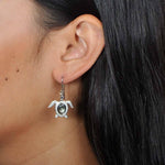 Sterling silver, abalone, and pave sea turtle hook earring worn by a model.