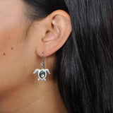 Sterling silver, abalone, and pave sea turtle hook earring worn by a model.