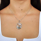 Sterling Silver, white topaz, and abole pendant designed like two dolphins. The pendant is worn by a model. 
