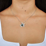 Sterling silver sea turtle pendant featuring Pave detail and an abalone shell. Worn by a model. 