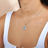 Sterling silver sand dollar pendant featuring Pave and iridescent abalone worn by a model.