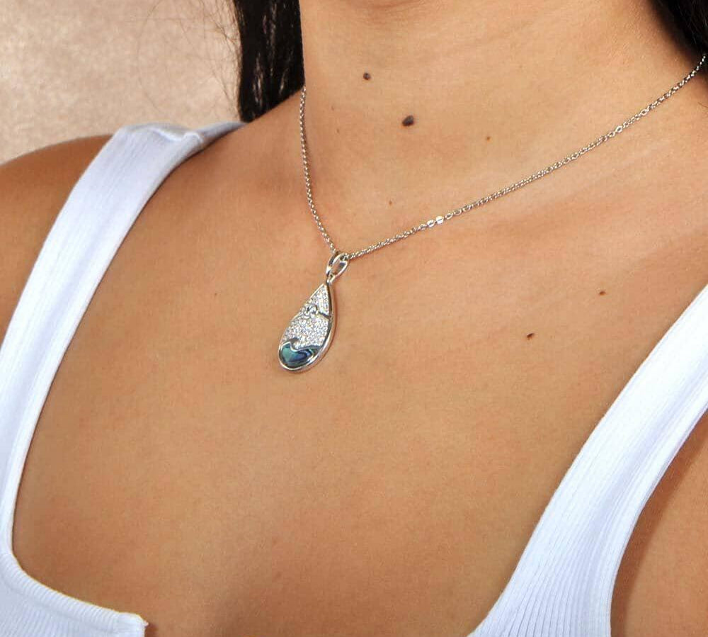 Abalone, white topaz, and sterling silver pendant featuring a sun and wave design, worn by a model. 
