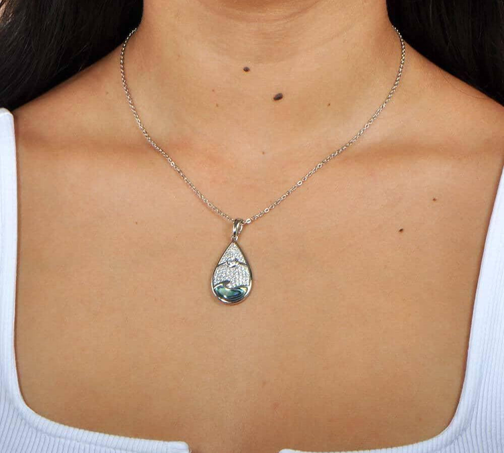 Abalone, white topaz, and sterling silver pendant featuring a sun and wave design, worn by a model. 