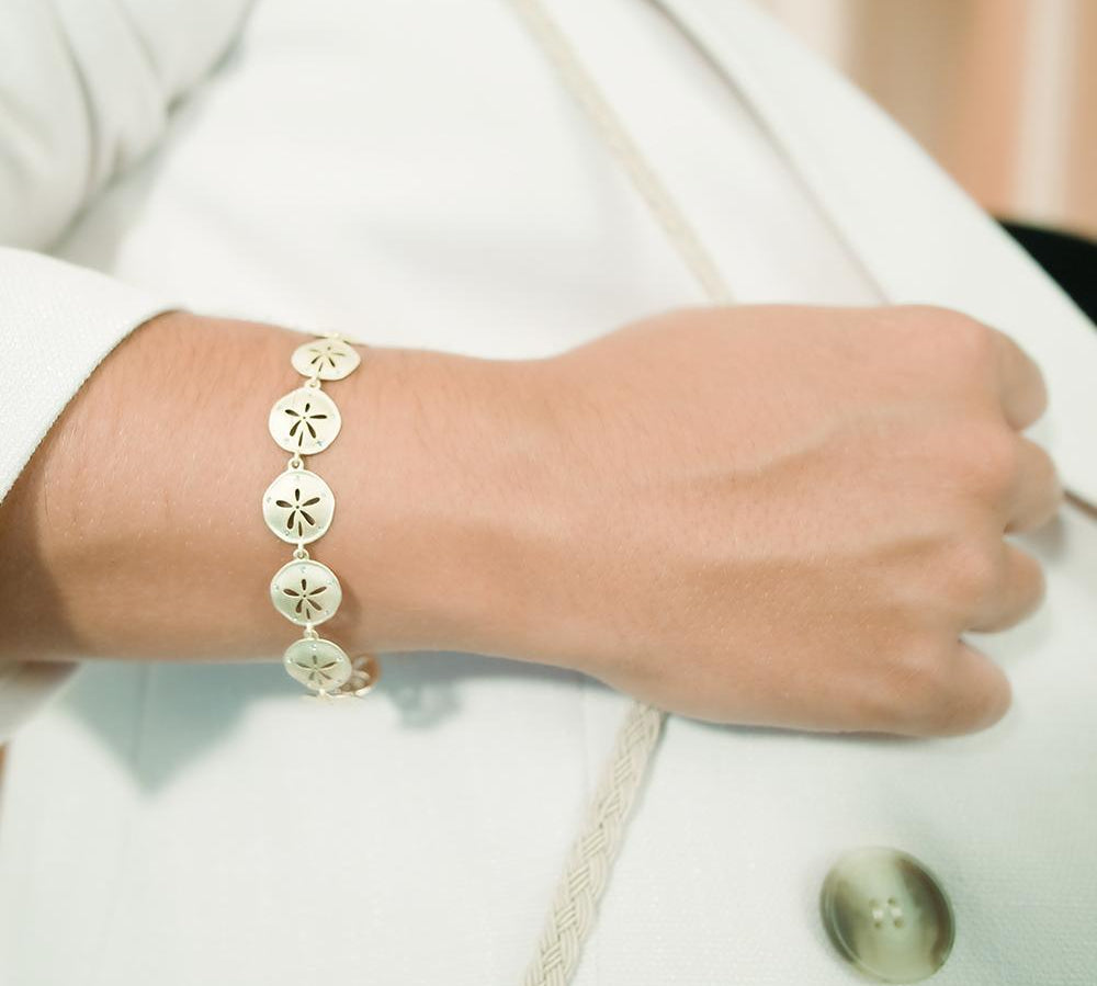 The picture shows a model wearing a 925 sterling silver yellow gold-plated sand dollar bracelet with topaz