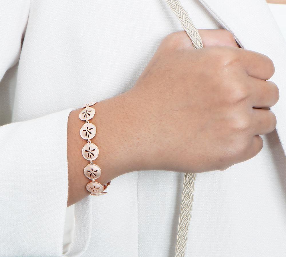 The picture shows a model wearing a 925 sterling silver rose gold-plated sand dollar bracelet with topaz
