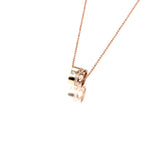 This picture shows a 14k yellow and rose gold two-tone barrel pendant with hand engravings and a diamond.