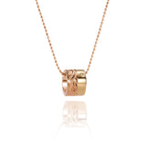 This picture shows a 14k yellow and rose gold two-tone barrel pendant with hand engravings and a diamond.