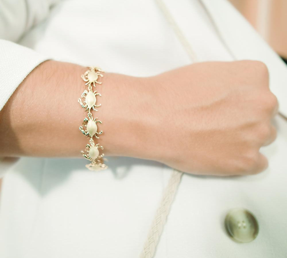 The picture shows a model wearing a 925 sterling silver yellow gold-plated blue crab bracelet.