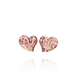In this photo there is a pair of 14k rose gold heart stud earrings with plumeria flower engravings.