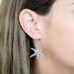 The picture shows a model wearing a 925 sterling silver starfish hook earring with topaz