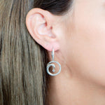 The picture shows a model wearing a 925 sterling silver drop of water lever-back earring with topaz and aquamarine.