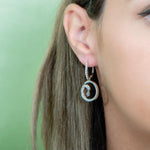 The picture shows a model wearing a 925 sterling silver drop of water lever-back earring with topaz and aquamarine.