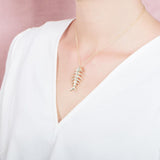 The picture shows a 925 sterling silver yellow gold vermeil fish bone pendant paired with cubic zirconia.