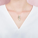 The picture shows a 925 sterling silver yellow gold vermeil fish bone pendant paired with cubic zirconia.