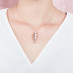 The picture shows a 925 sterling silver rose gold vermeil fish bone pendant paired with cubic zirconia.