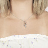 In this picture there is a model with blonde hair and a white shirt with purple flowers wearing a sterling silver heliconia pendant.