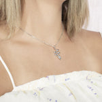 In this picture there is a model with blonde hair and a white shirt with purple flowers turned to the right wearing a sterling silver heliconia pendant.