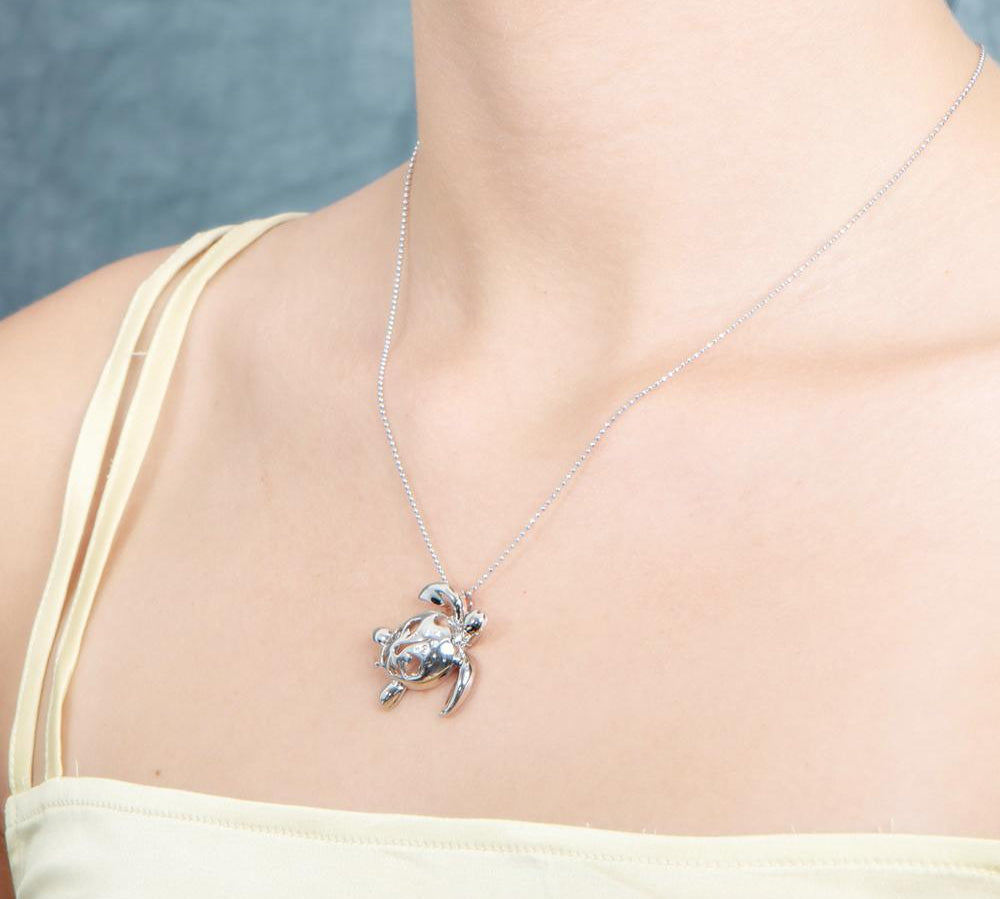 The picture shows a model wearing a 925 sterling silver sea turtle pendant with hibiscus cut-out and cubic zirconia.