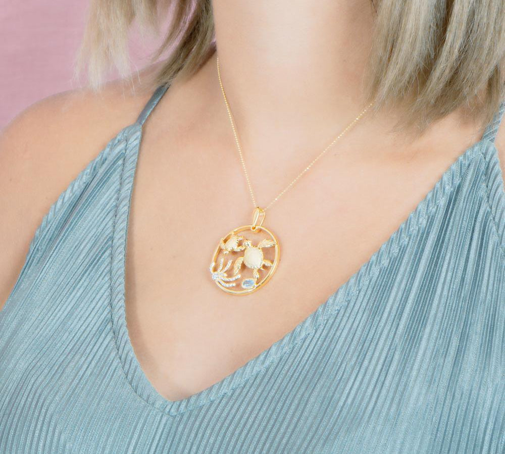 The picture shows a 925 sterling silver, yellow gold plated, eternity pendant with two sea turtles and seaweed with  aquamarine.
