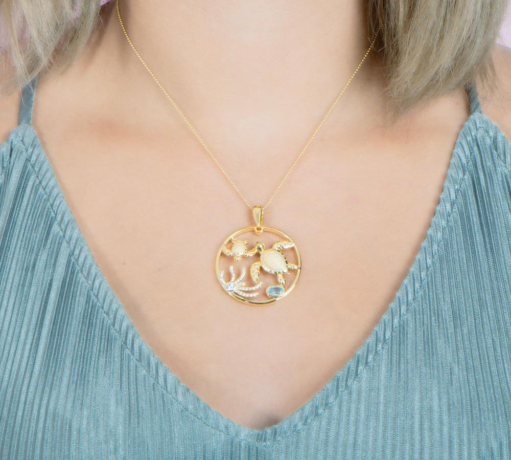 The picture shows a 925 sterling silver, yellow gold plated, eternity pendant with two sea turtles and seaweed with  aquamarine.