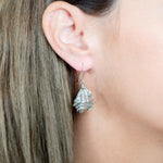 The picture shows a model wearing a 925 sterling silver conch shell earring.