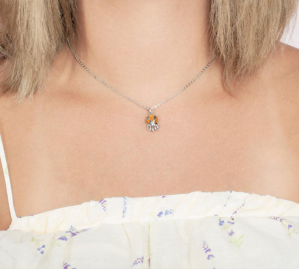Model wearing a pendant made of Koa wood, and sterling silver designed as an octopus