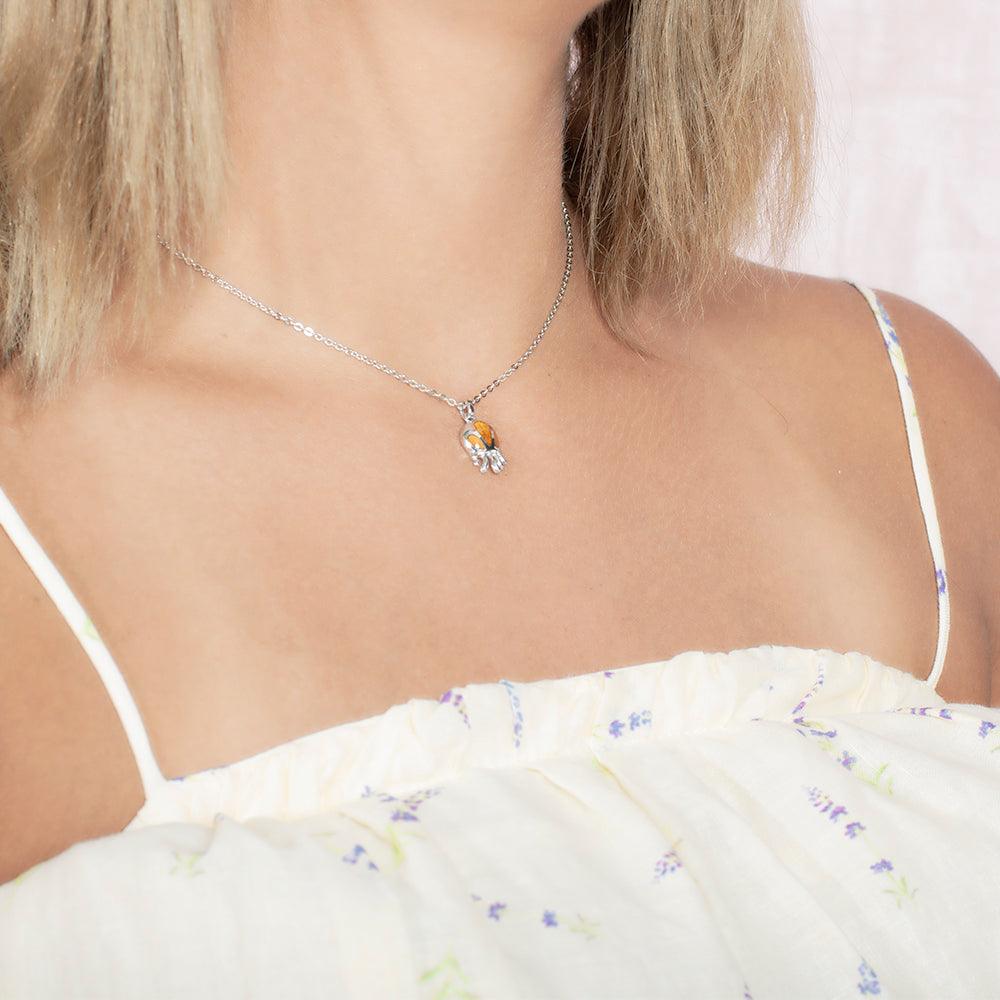 Model wearing a pendant made of Koa wood, and sterling silver designed as an octopus, but the image is taken at an angle. 
