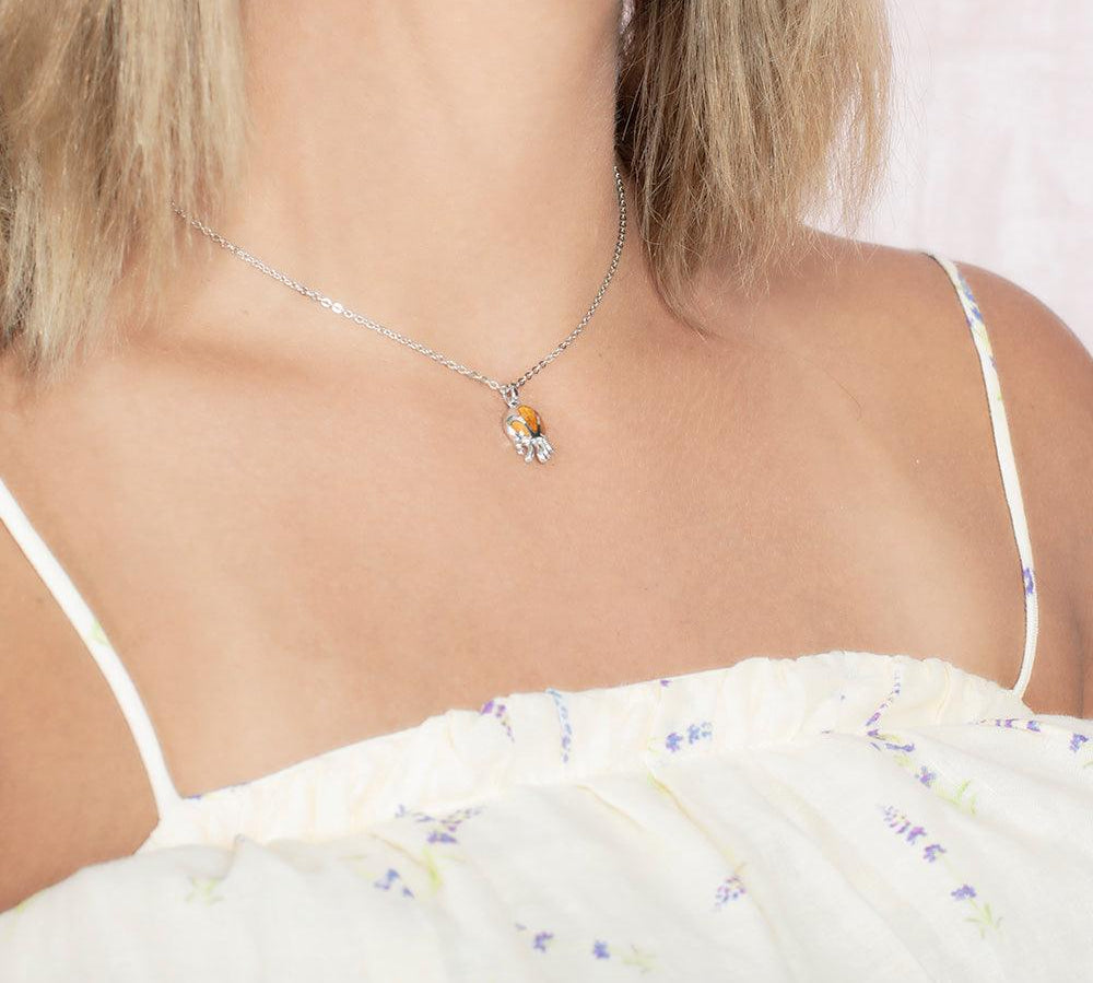 Model wearing a pendant made of Koa wood, and sterling silver designed as an octopus, but the image is taken at an angle. 