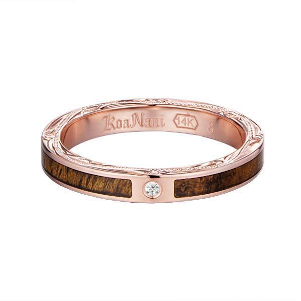 In this photo there is a rose gold koa wood ring with hand engravings of scrolls and one diamond.