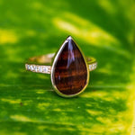 14k gold Koa wood tear drop ring with diamonds embedded in the band.