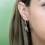 The picture shows a model wearing a 925 sterling silver starfish lever-back earring with topaz