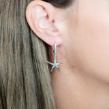 The picture shows a model wearing a 925 sterling silver starfish lever-back earring with topaz