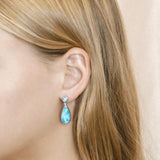 The picture shows a model wearing a 925 sterling silver larimar teardrop earring.