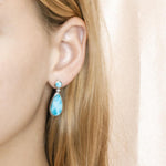 The picture shows a model wearing a 925 sterling silver larimar teardrop earring.
