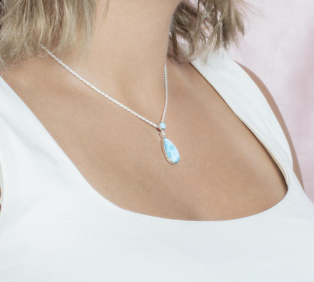 The picture shows a model wearing a 925 sterling silver larimar teardrop pendant with topaz.