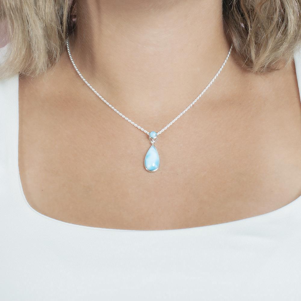 The picture shows a model wearing a 925 sterling silver larimar teardrop pendant with topaz.
