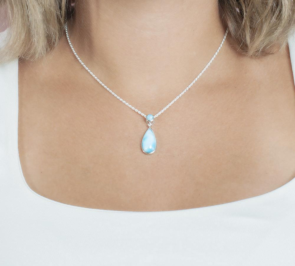 The picture shows a model wearing a 925 sterling silver larimar teardrop pendant with topaz.