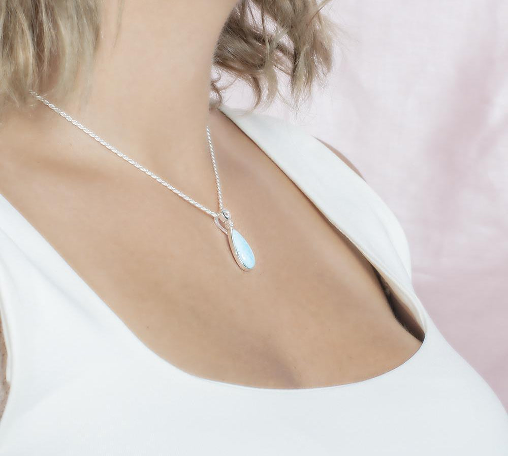The picture shows a model wearing a 925 sterling silver larimar teardrop pendant with aquamarine and cubic zirconia.
