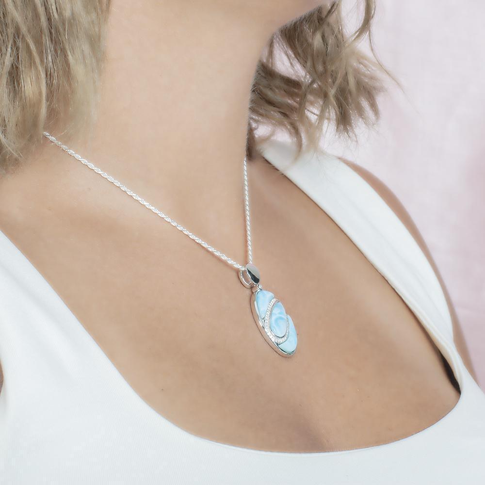 The picture shows a model wearing a 925 sterling silver larimar pendant with aquamarine and topaz.