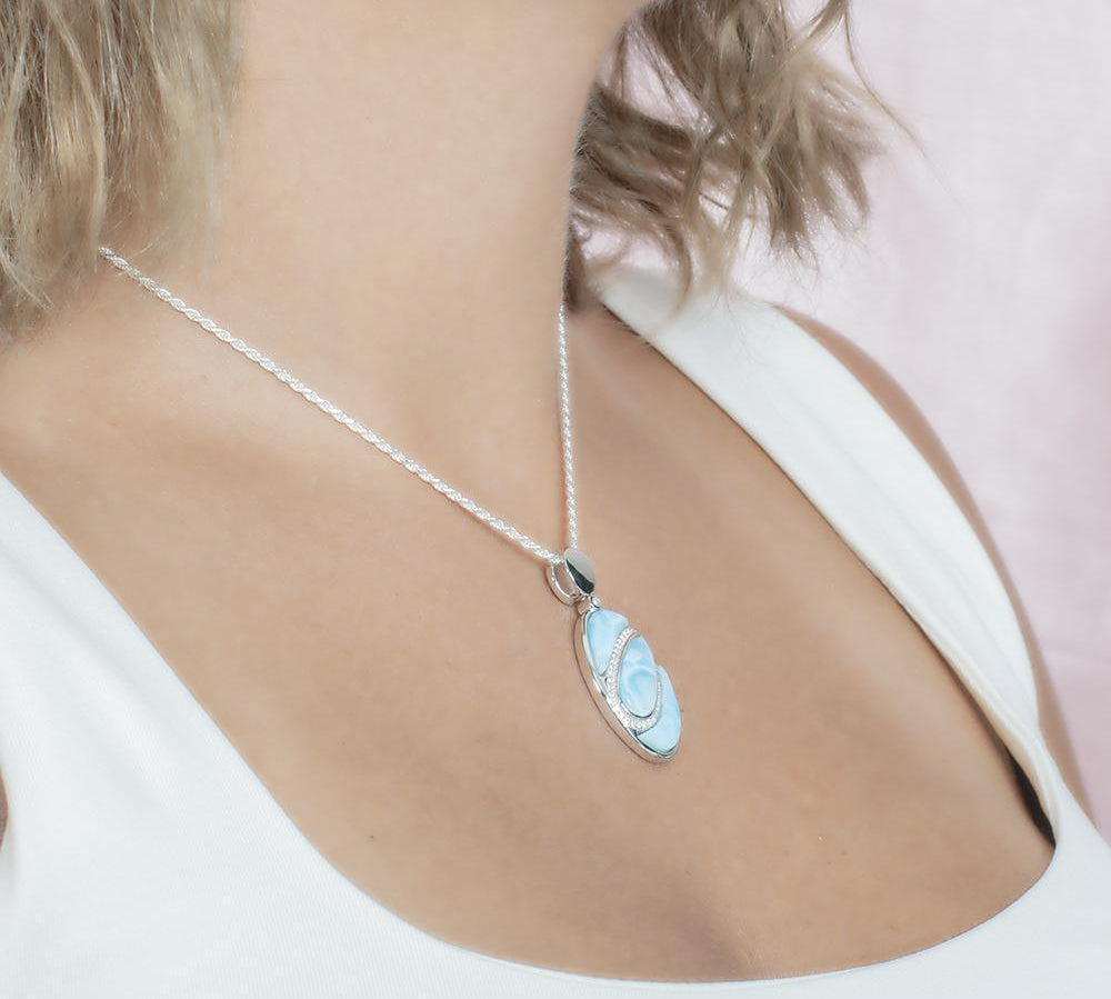 The picture shows a model wearing a 925 sterling silver larimar pendant with aquamarine and topaz.