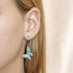 In this photo there is a model wearing 925 sterling silver butterfly hook earrings with blue larimar and topaz gemstones.