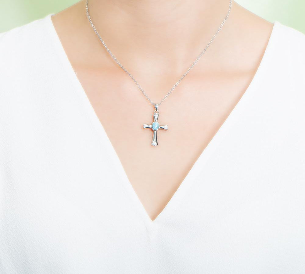 The picture shows a model wearing a 925 sterling silver larimar centered cross pendant.