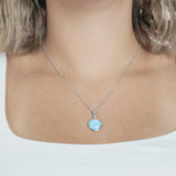 The picture shows a model wearing a 925 sterling silver larimar circle pendant.