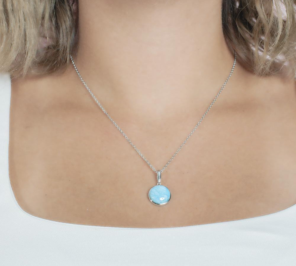 The picture shows a model wearing a 925 sterling silver larimar circle pendant.