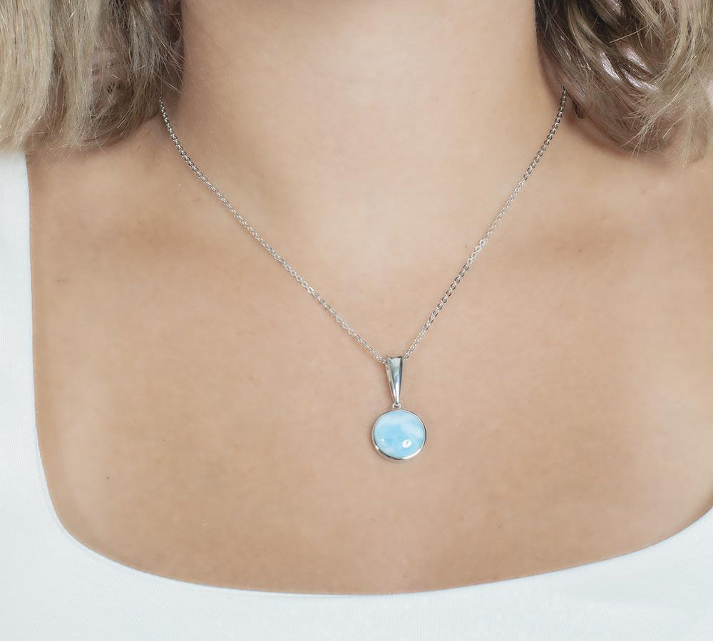 The picture shows a model wearing a 925 sterling silver larimar circle pendant.