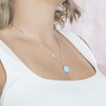 The picture shows a model wearing a 925 sterling silver larimar circle pendant.